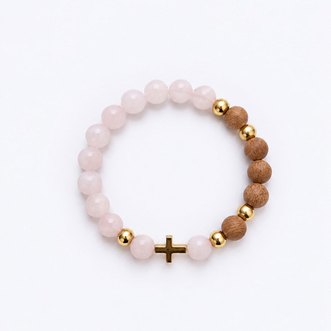 A beaded stretch bracelet featuring light pink rose quartz beads, natural brown wood beads, polished gold spacer beads, and a small gold cross charm, displayed on a clean white background.