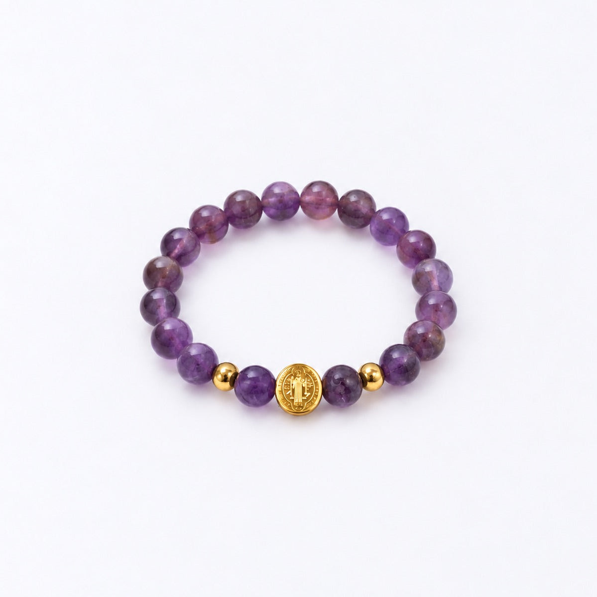 A purple gemstone beaded bracelet with two small gold spacer beads and a central gold round charm featuring a St Benedict symbol, displayed on a clean white background.
